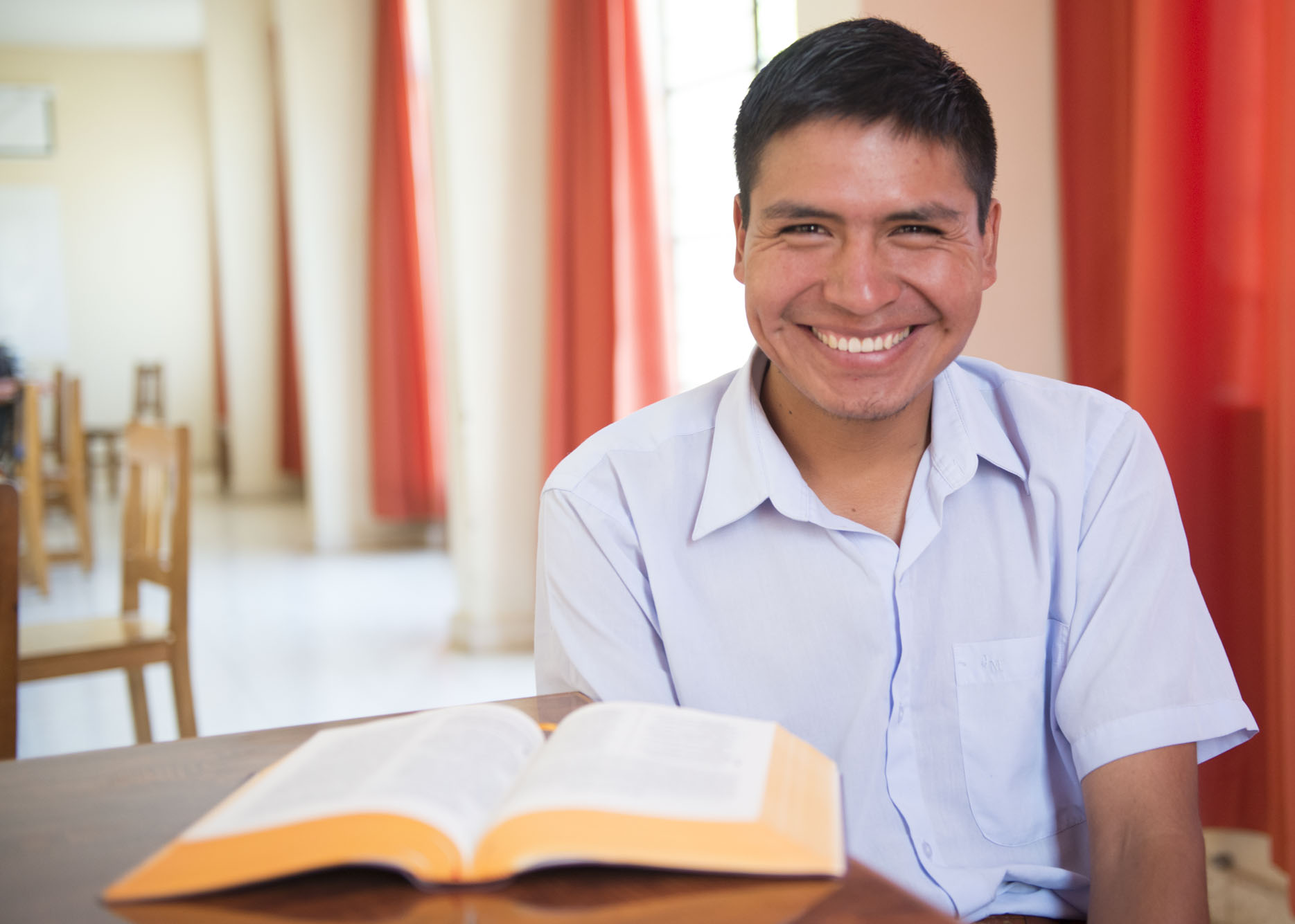 A translator smiles with an open New Testament.